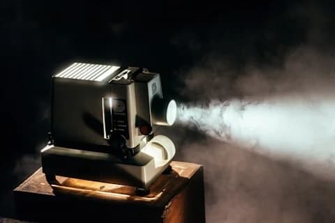 Vintage film projector beaming light through haze